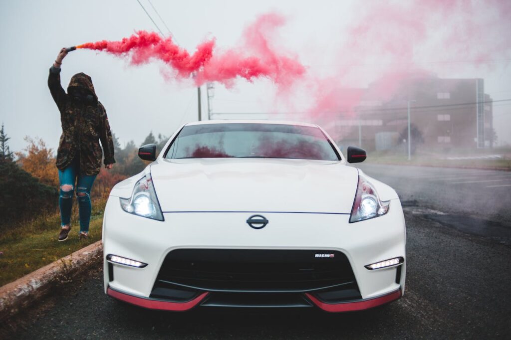 Woman with colored smoke bomb near modern car